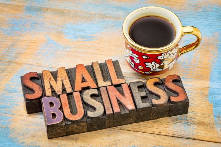 Small Business sign on table next to cup of coffee.
