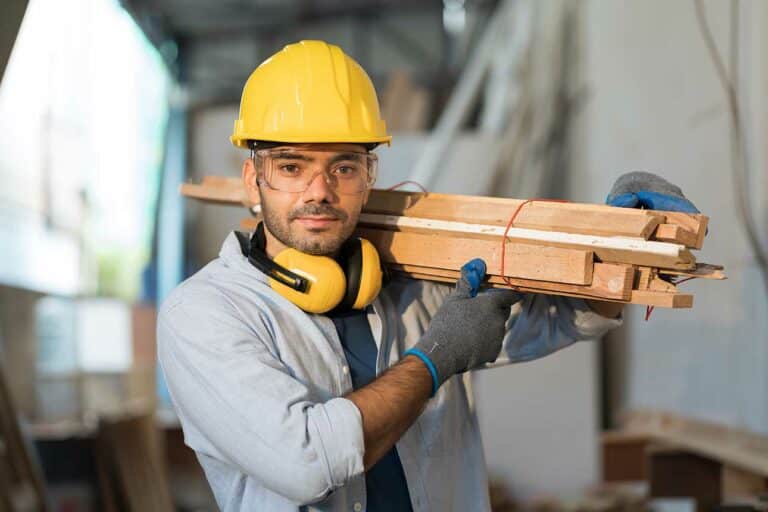 Contractors employee working on the job carrying wood