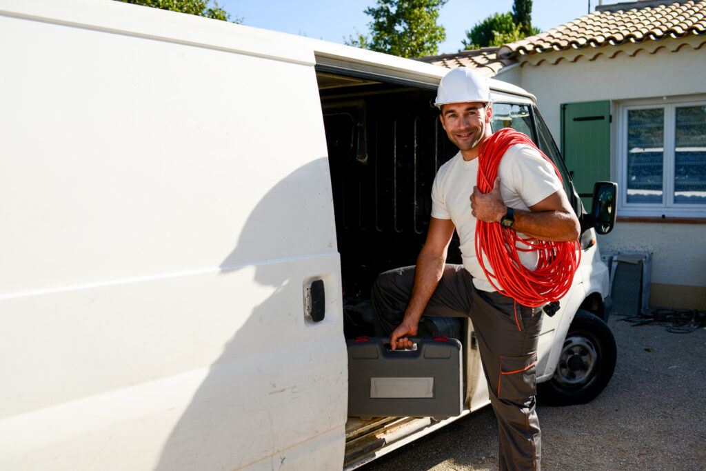 young electrician artisan taking tools out of his professional truck van